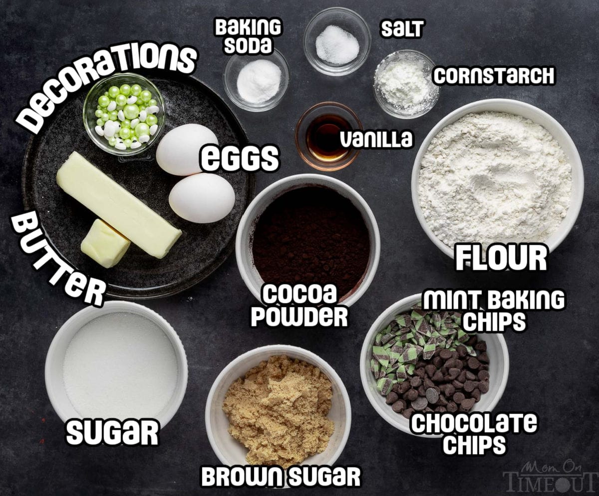 A photo that shows all of the ingredients for halloween monster cookies laid out on a dark surface.