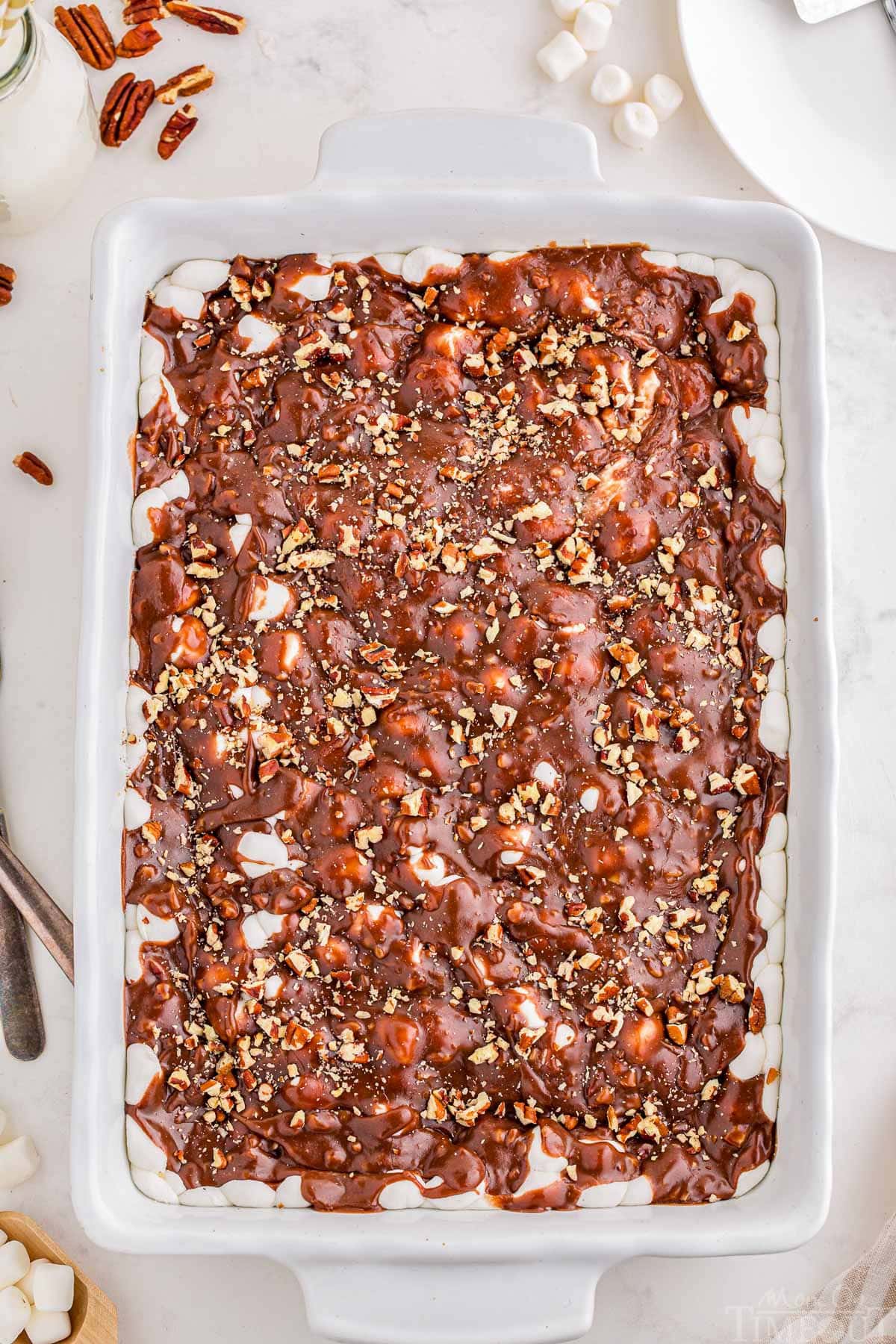 Top down view of a ready to be served Mississippi Mud Cake in a white baking dish. Pecans are scattered next to the dish.