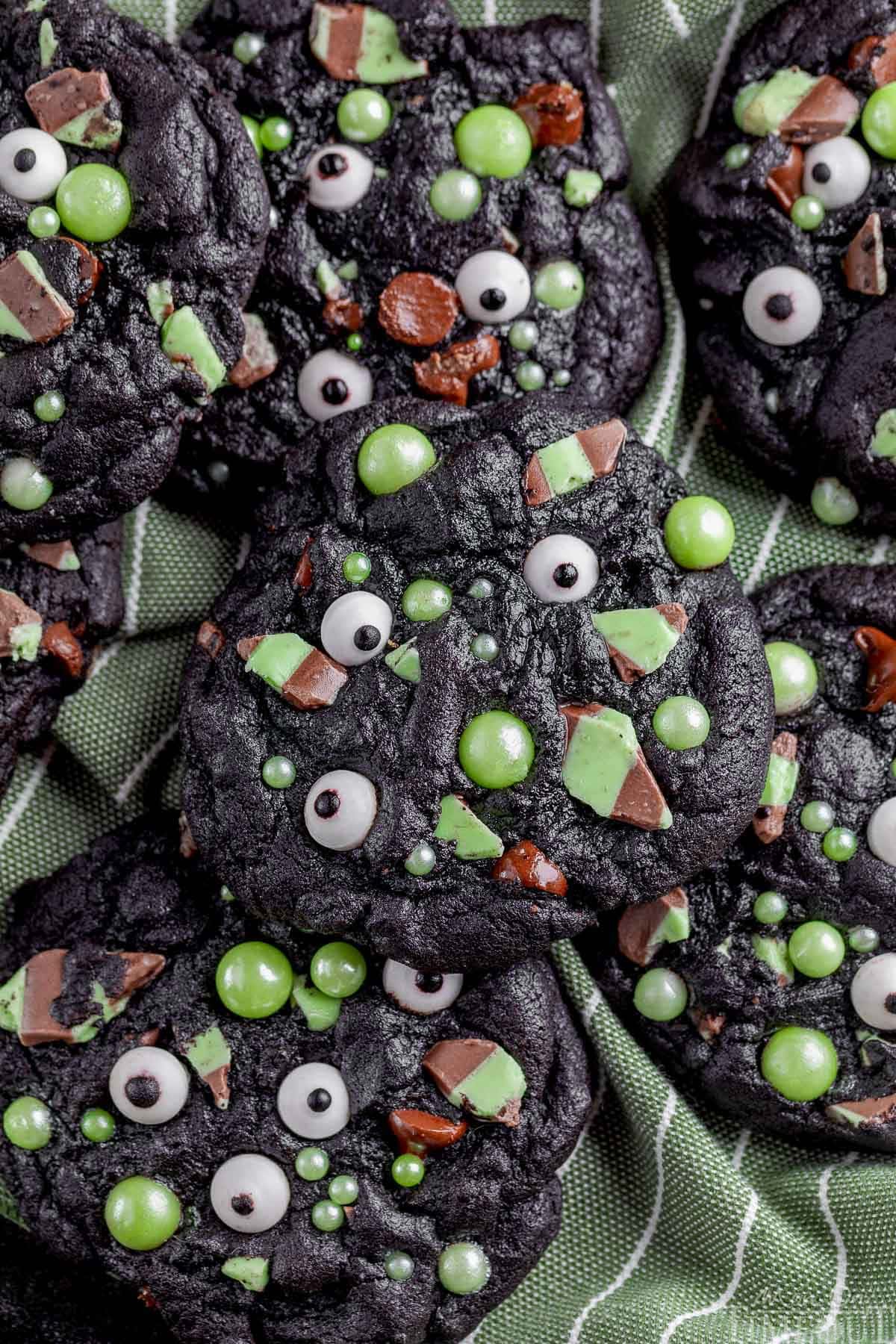 A pile of monster halloween cookies on a green cloth.