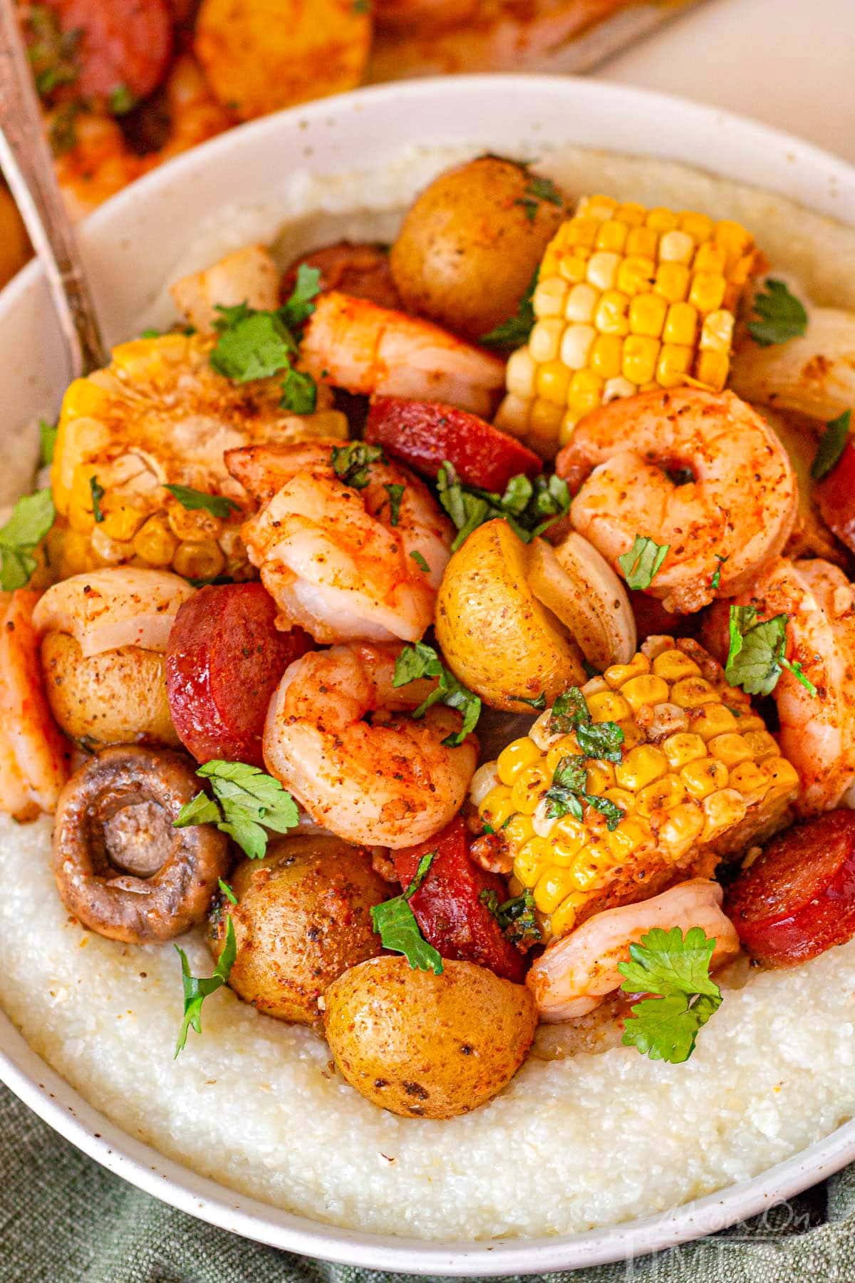 Close up of the old bay shrimp boil in a bowl with grits and garnished with parsley.