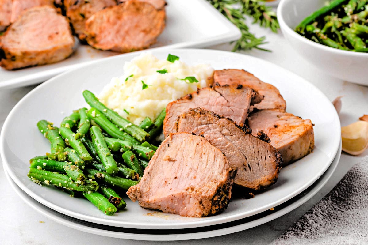 Dinner plate with air fryer pork tenderloin cut into medallions, green beans and mashed potatoes.