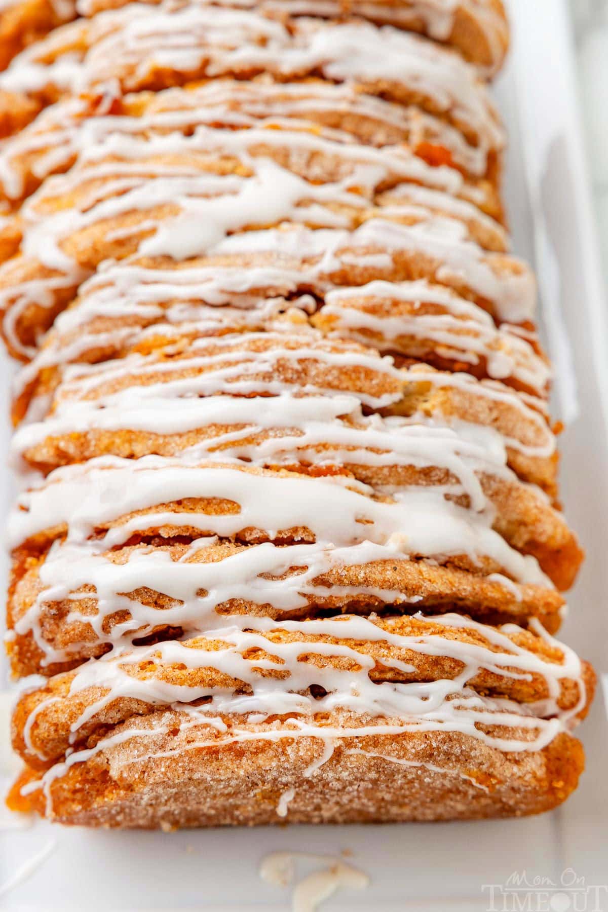 Close up look at the pull apart pumpkin loaf with a vanilla glaze on a white plate.