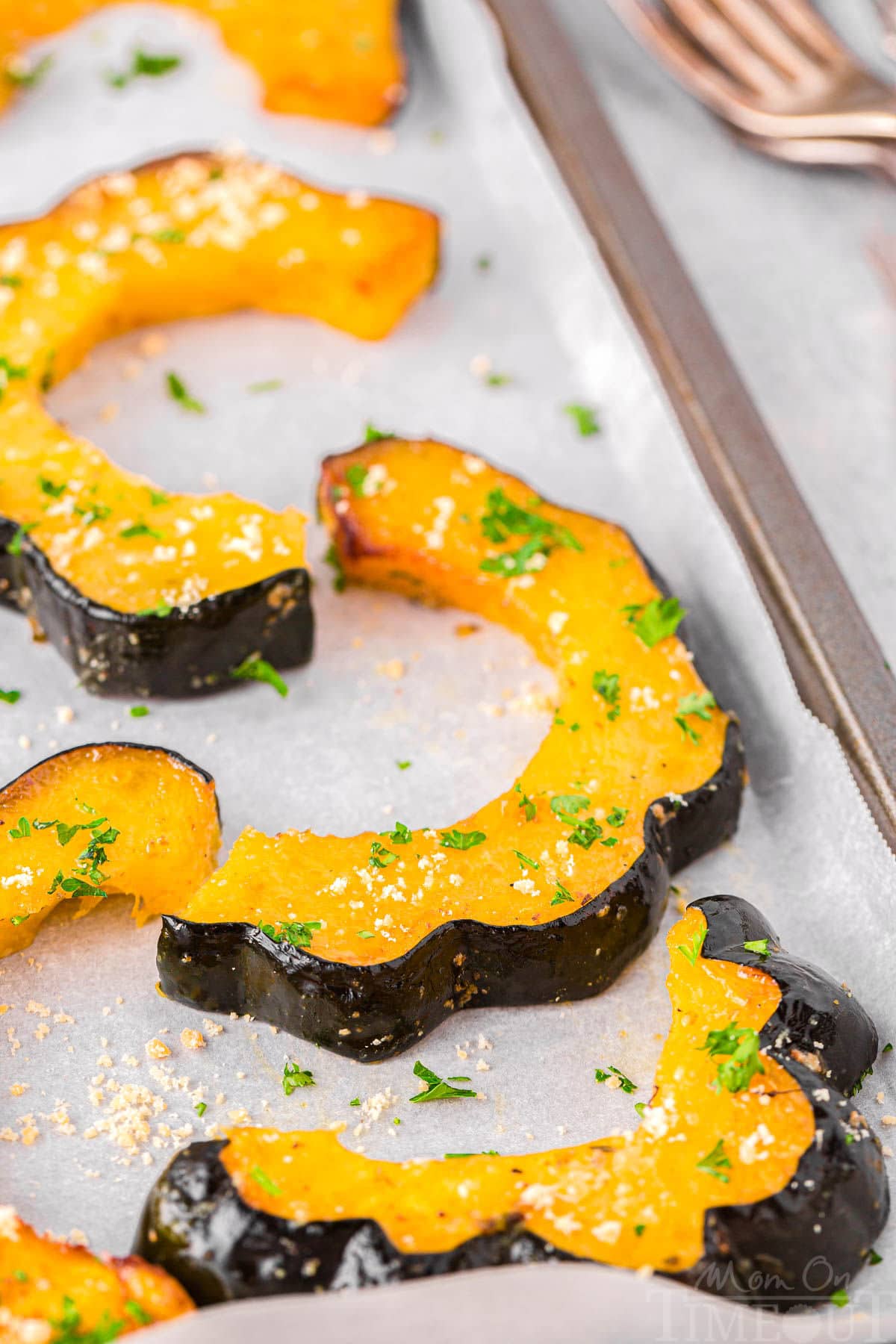 Roasted acorn squash slices on sheet pan lined with parchment paper.