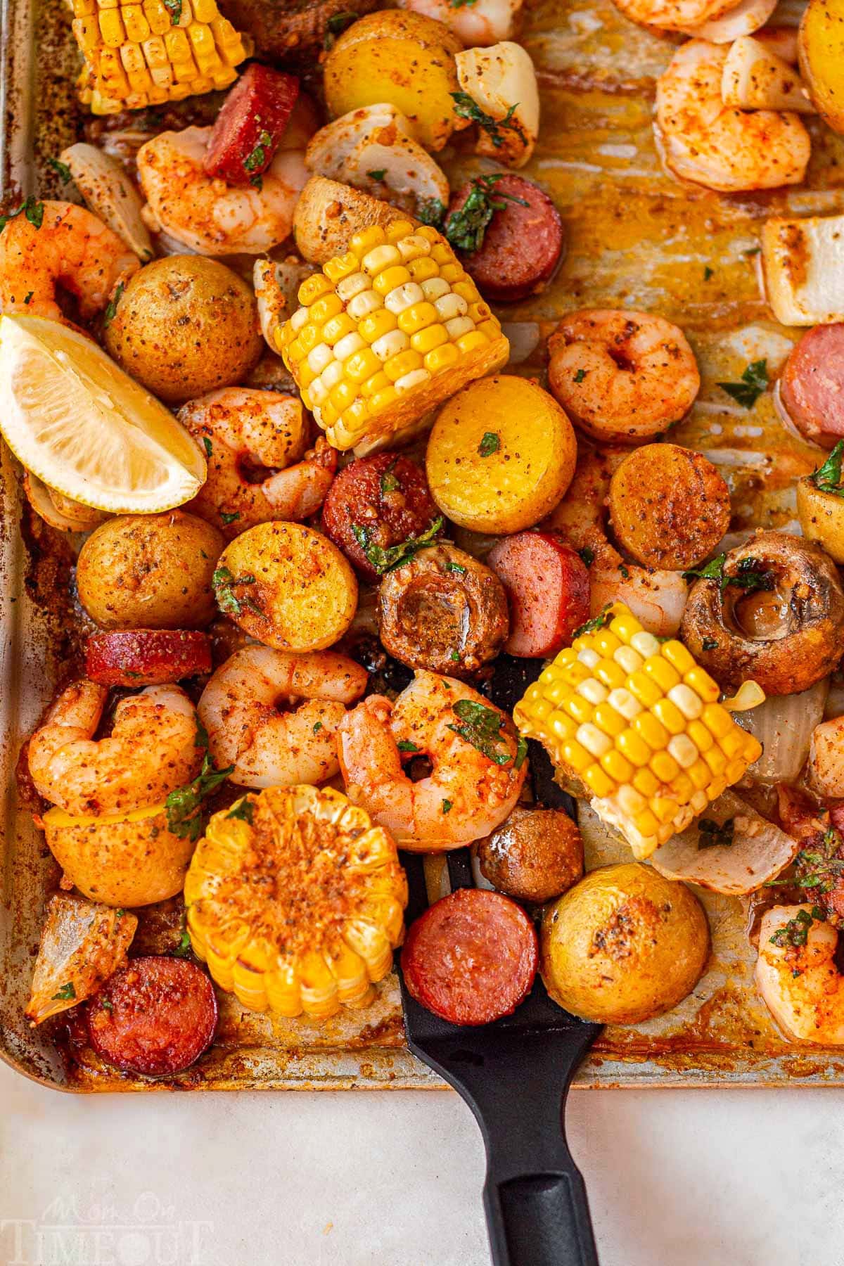 Sheet pan shrimp boil cooked and ready to be served right off the pan. Lemon wedges garnish the boil.