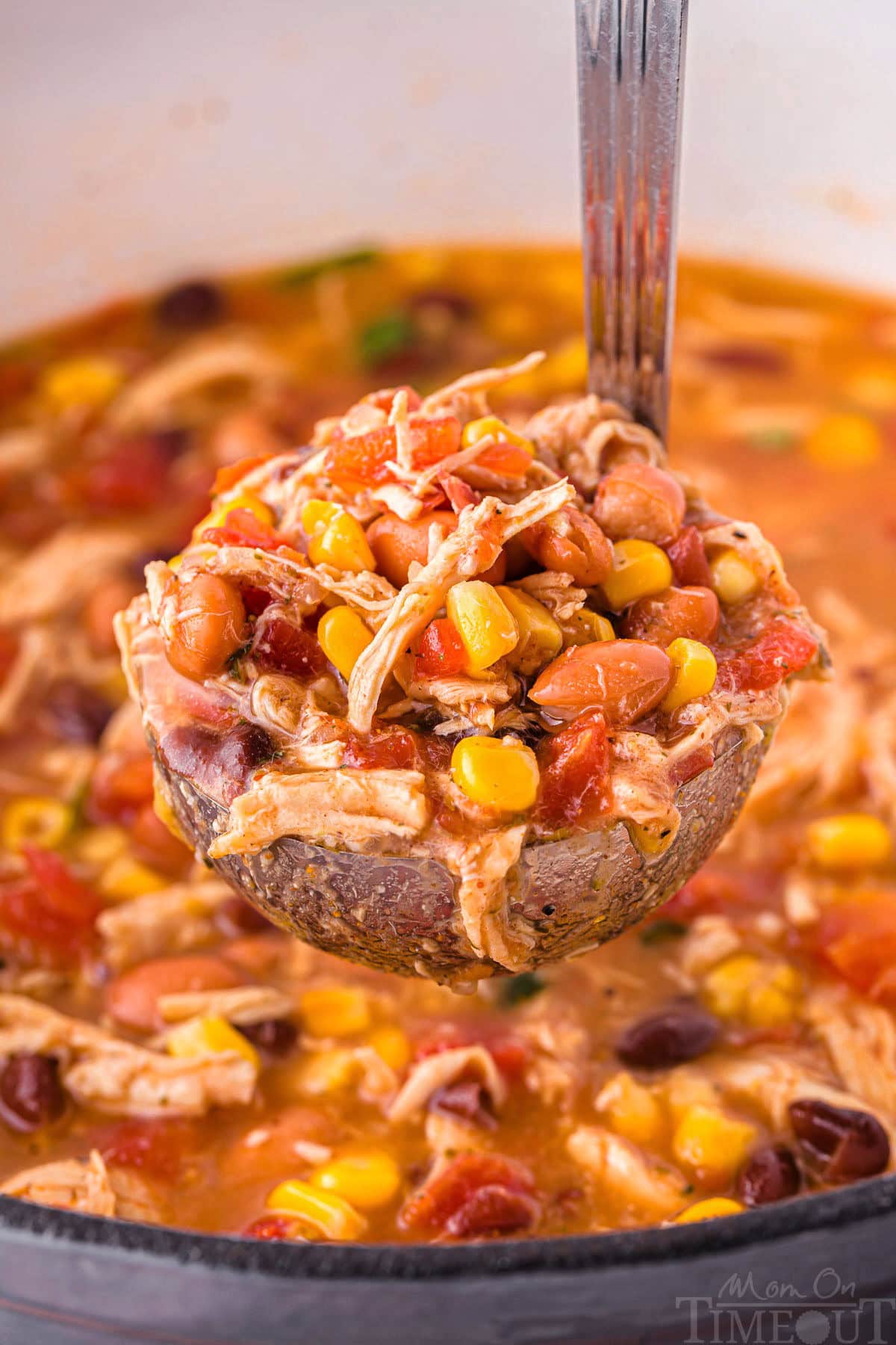 A soup ladle holding a scoop of chicken taco soup over the pot of soup.