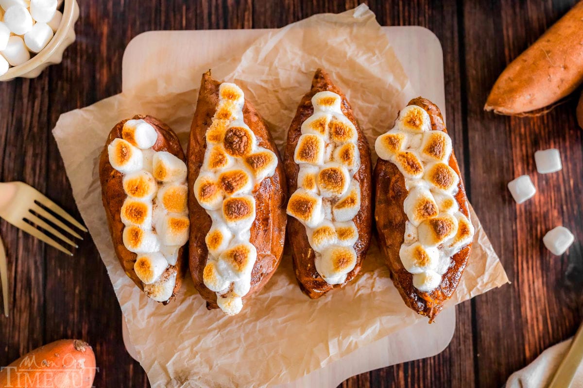 Twice baked sweet potatoes on a piece of parchment paper that's on a wood cutting board.