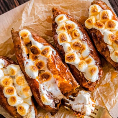 Twice baked sweet potatoes on a piece of parchment paper with a gold fork digging into a potato.