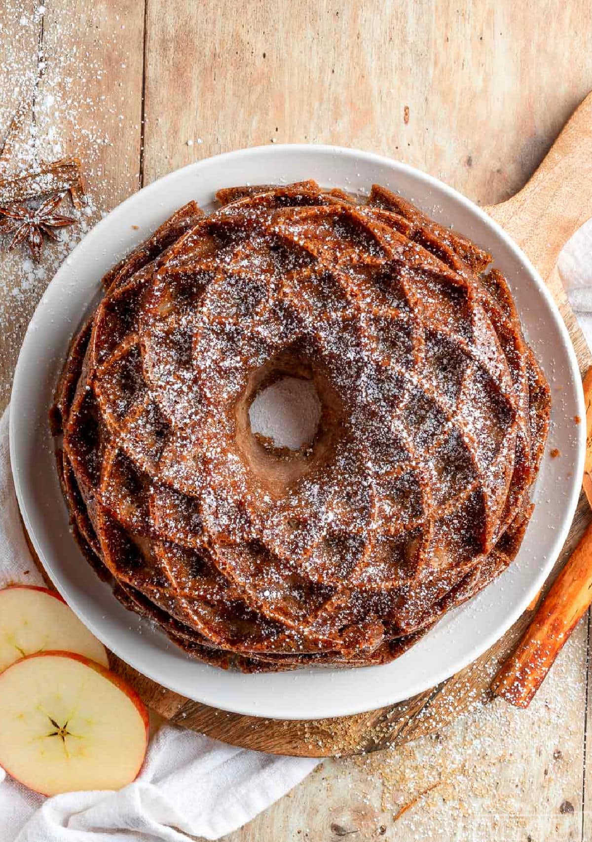 Top down view of the apple bundt cake dusted with powdered sugar. The cake is sitting on a white plate.