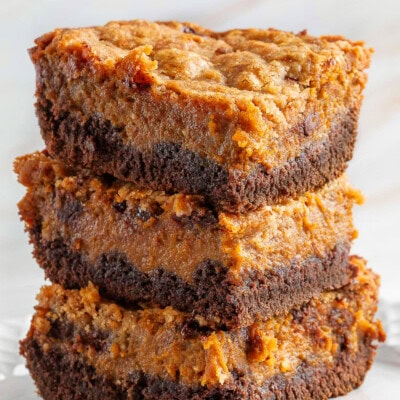 A stack of chocolate pumpkin cheesecake bars on a white plate.