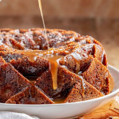 Caramel glaze being drizzled on top of the apple bundt cake.