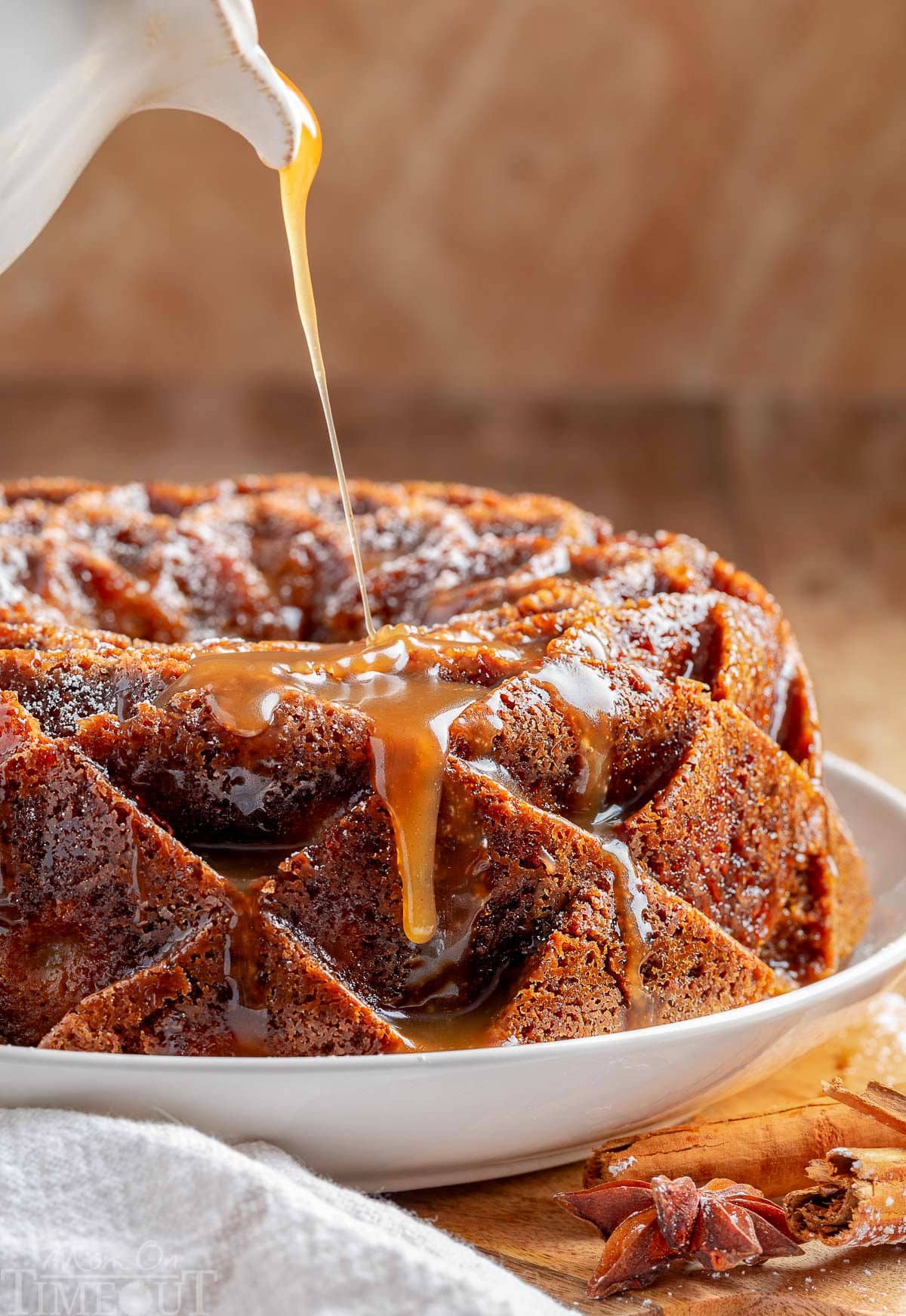 Caramel glaze being drizzled on top of the apple bundt cake.