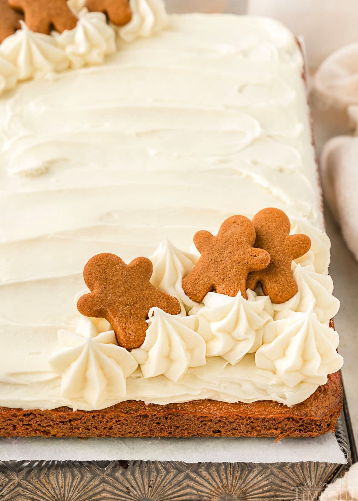 A side view of gingerbread cake topped with cream cheese frosting and gingerbread men.