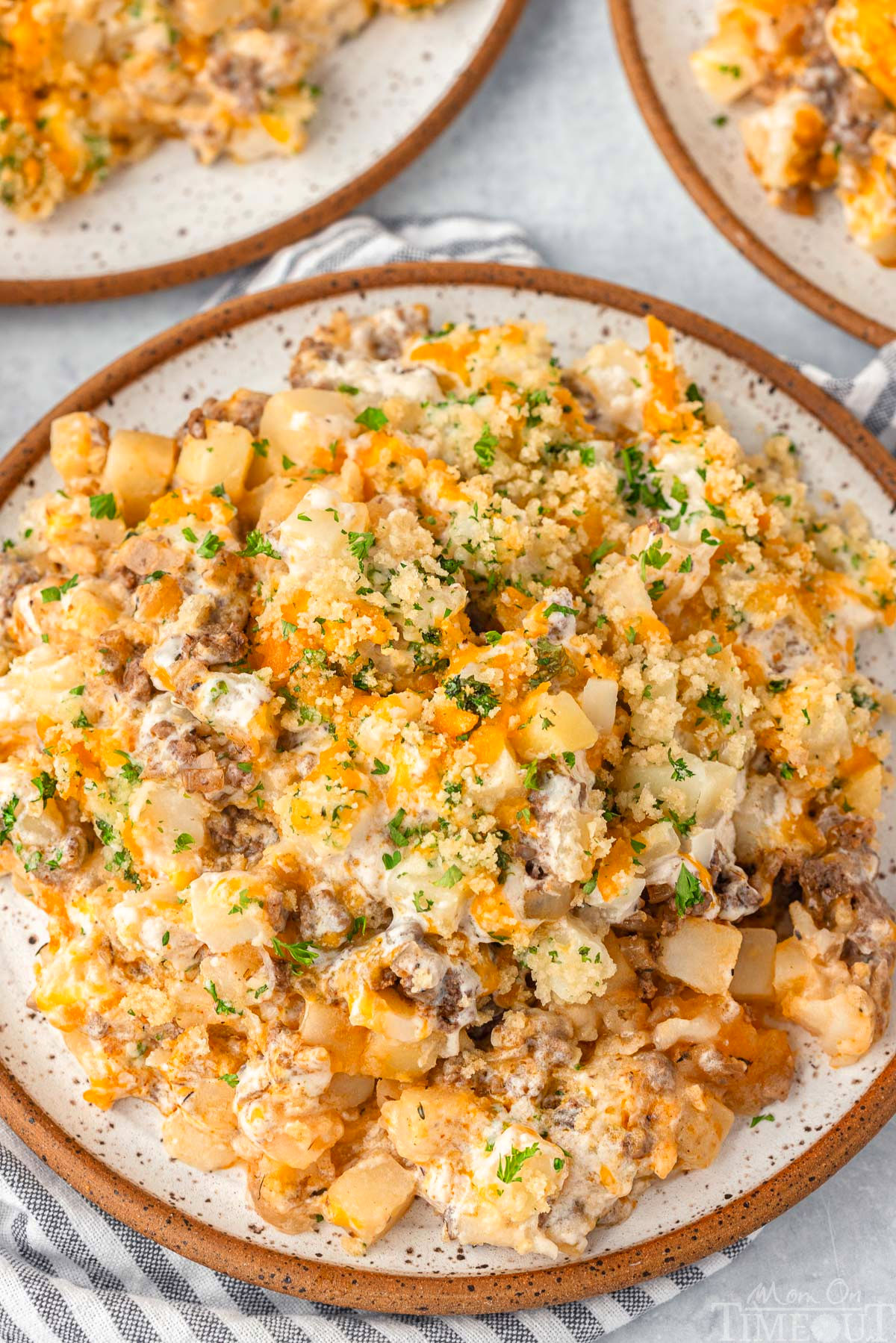 Top down look at ground beef and potato casserole plated on a round inner plate and topped with chopped parsley.