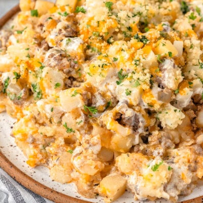 Top down look at ground beef and potato casserole plated on a round inner plate and topped with chopped parsley.