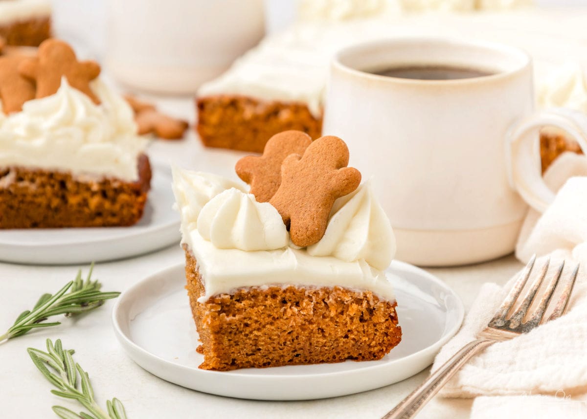 A slice of gingerbread cake topped with gingerbread men. The cake is on a white plate.