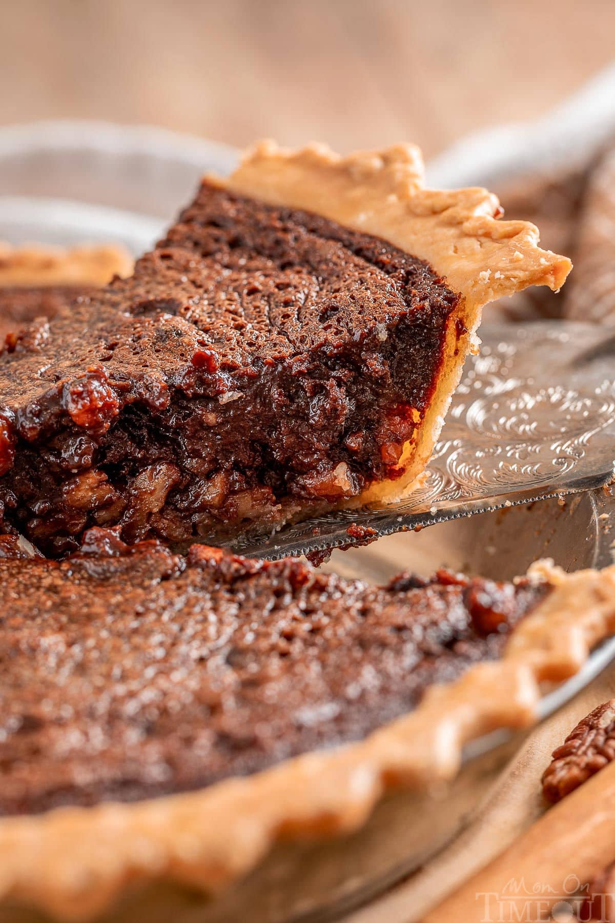 Slice of chocolate pecan pie with bourbon being lifted out of pie plate.