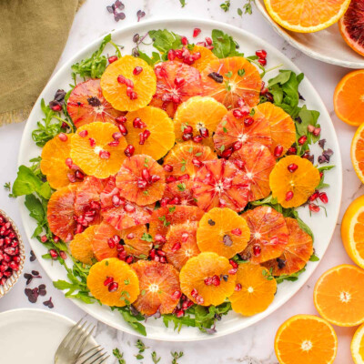 Top down view of vibrant citrus salad made with blood oranges, oranges, arugula and thyme and dressed with a citrus salad dressing.