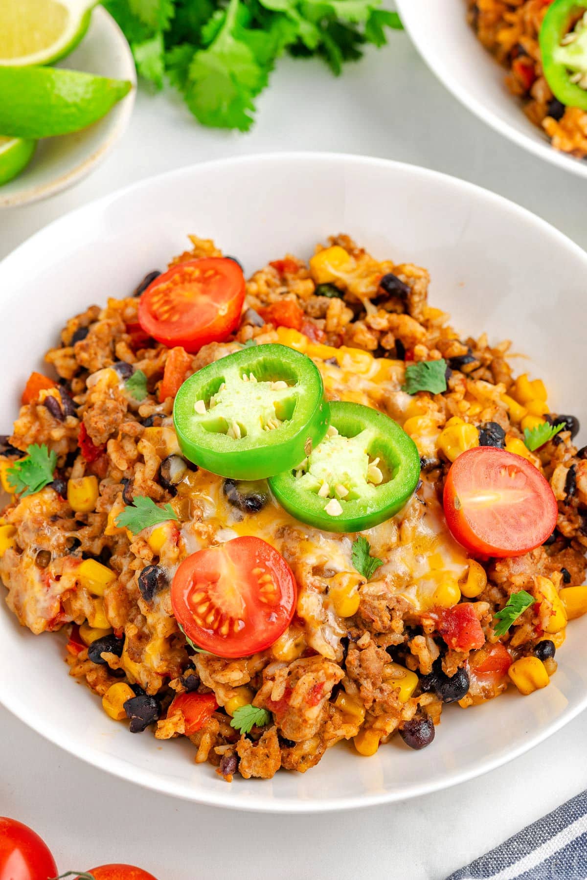 Ground turkey taco skillet rice in a white bowl topped with tomatoes and jalapenos. 