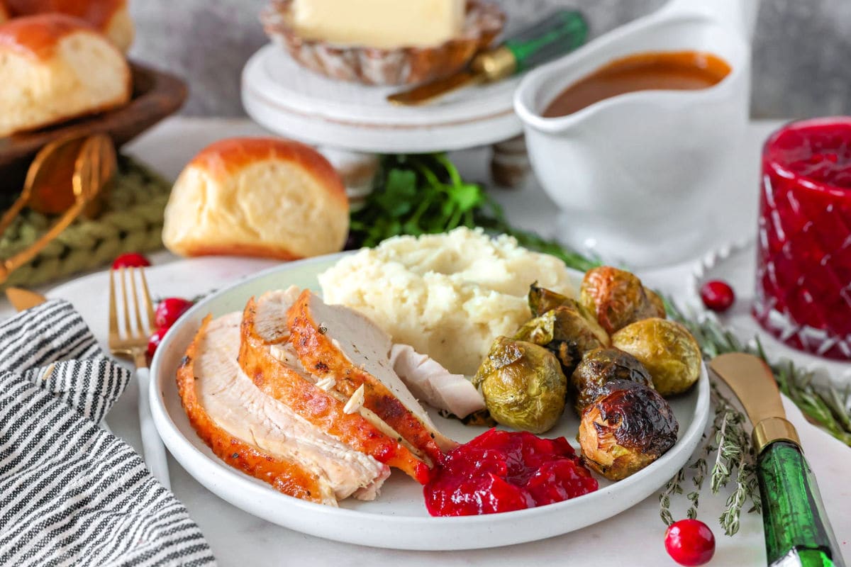 Image showing how much turkey per person on a plate with classic Thanksgiving side dishes.