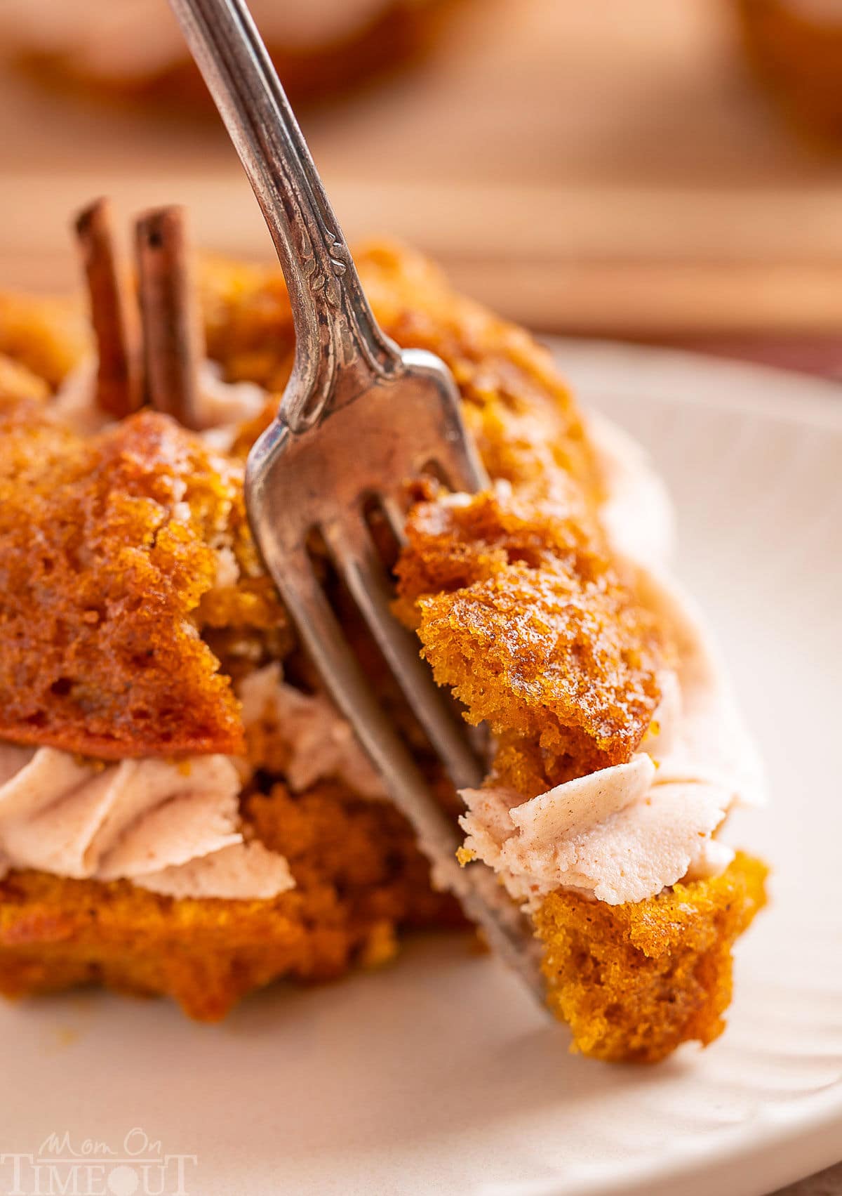 Forkful of pumpkin bundt cake being removed from the cake. Tender, moist cake and creamy frosting are shown on the fork.