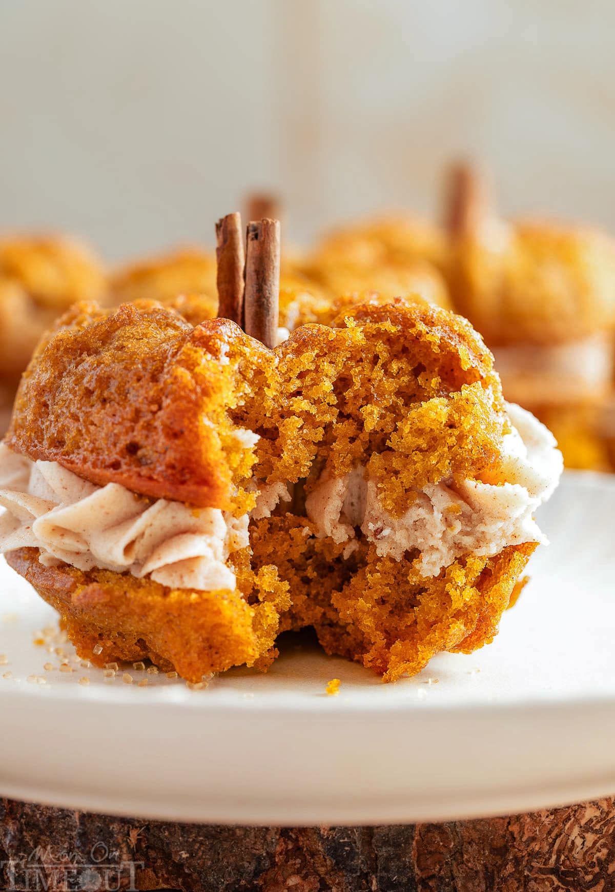 Pumpkin bundt cake on white round plate. Bite of the cake has been taken revealing the frosting layer between the two cakes.