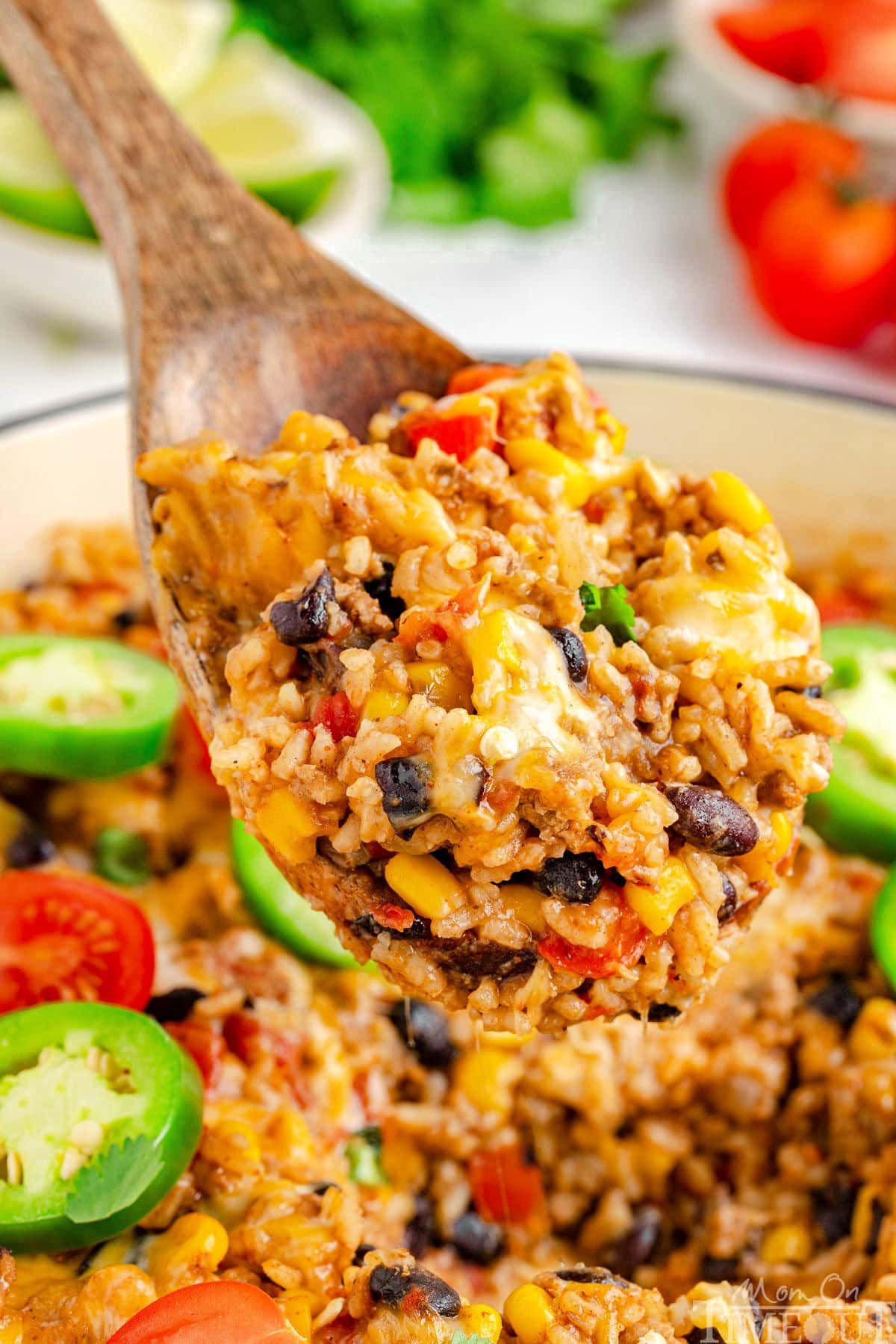 Wood spoon scooping out a serving of taco rice from a white skillet.