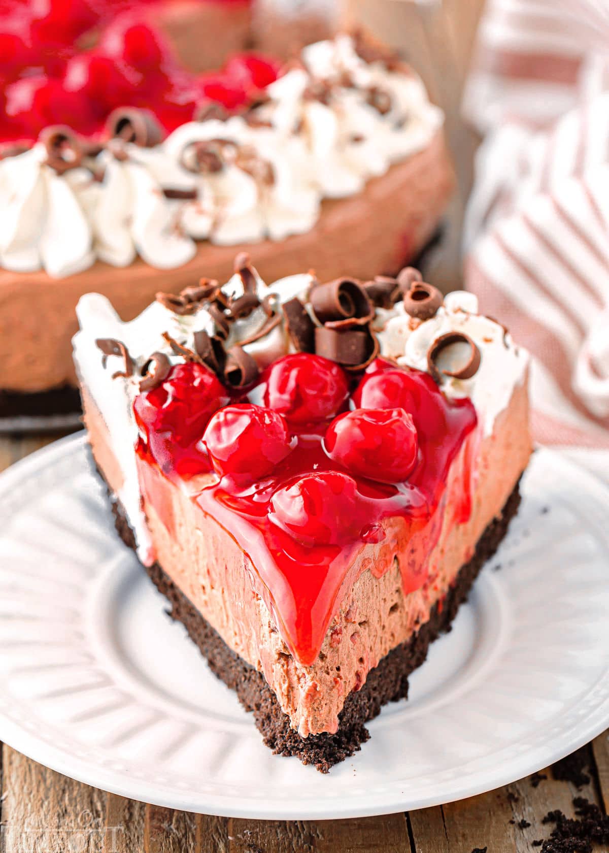 Slice of black forest cheesecake on white round plate.