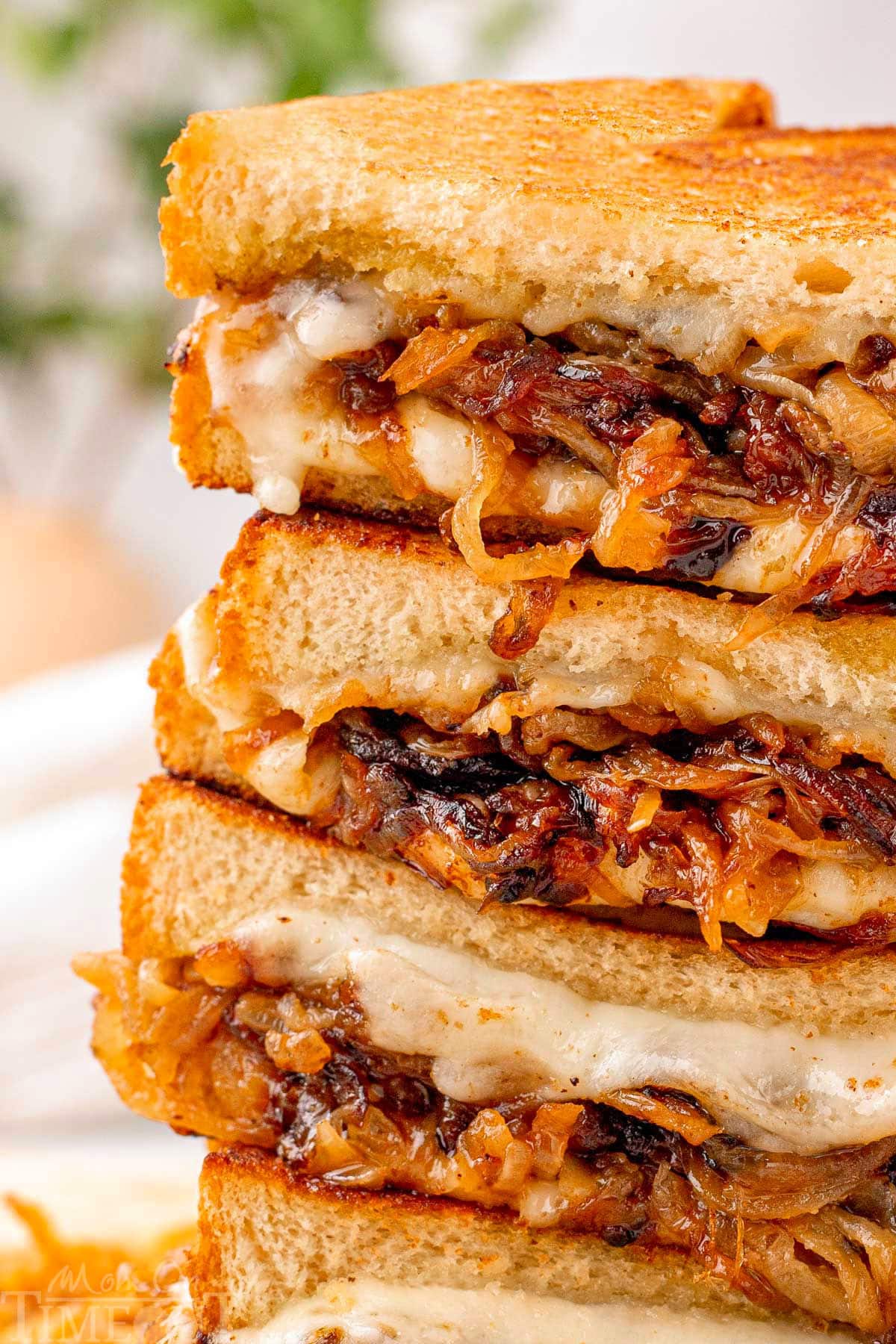 Close up look at caramelized onion grilled cheese cut in halve and stacked four high.