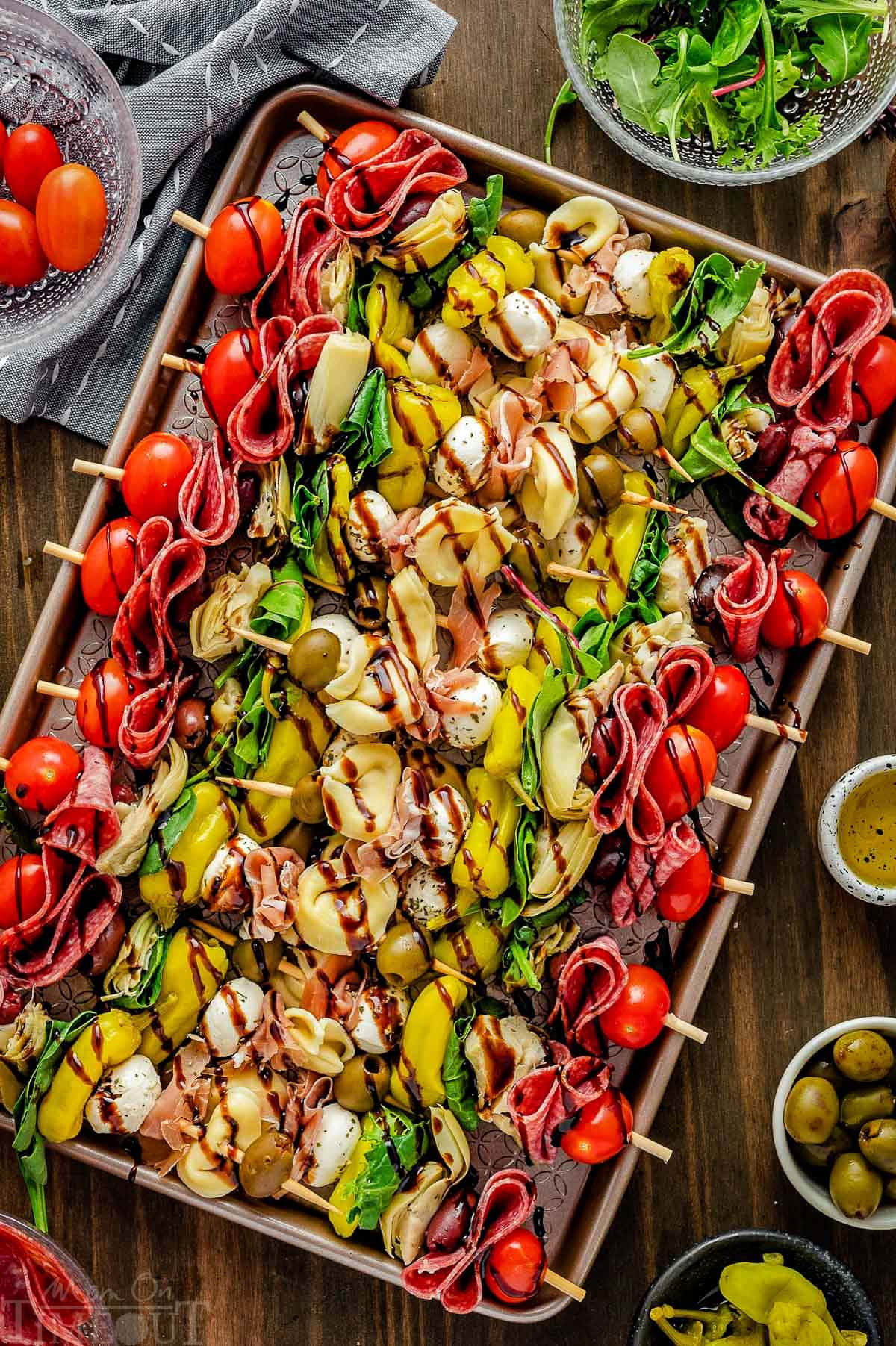 Top down view of antipasto skewers on a sheet pan drizzled with balsamic glaze and ready to eat.