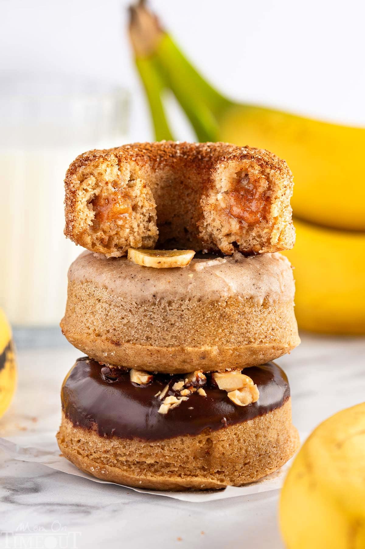 Banana Donuts stacked on top of each other. Bananas are in the background.