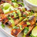 Close up view of slices of Peruvian Chicken drilled with Aji Verde on a white serving plate.