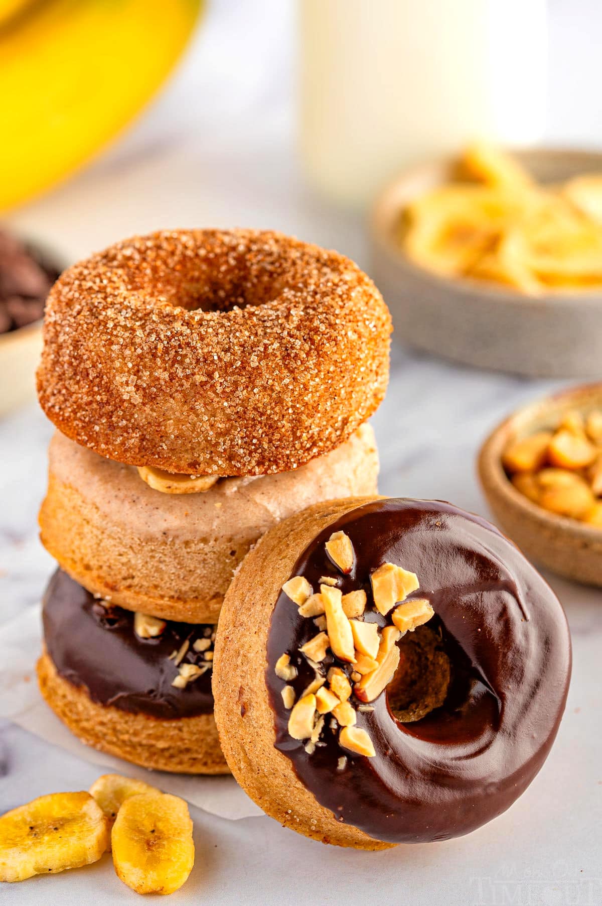 Stack of banana donuts with a chocolate glazed donut leaning against the stack.